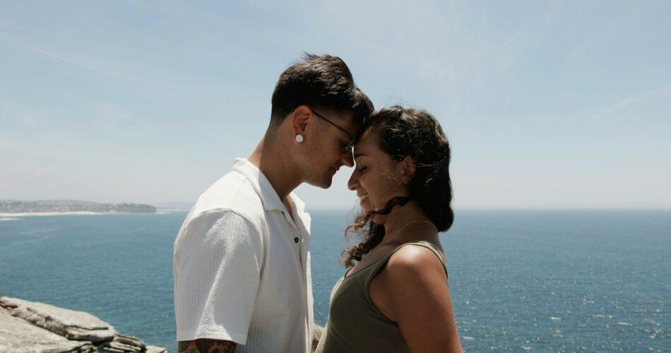 a man and woman standing next to each other near the ocean