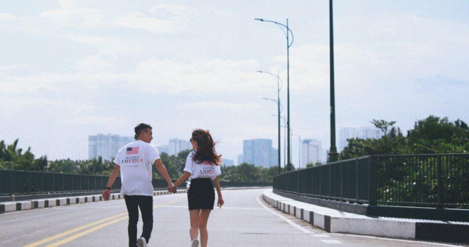 man and woman holding hands while walking on street