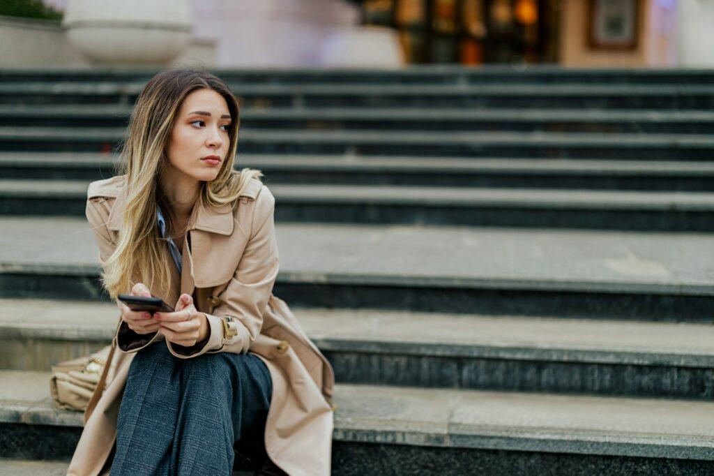 Woman receiving bad news on a smartphone while sitting on a stairs