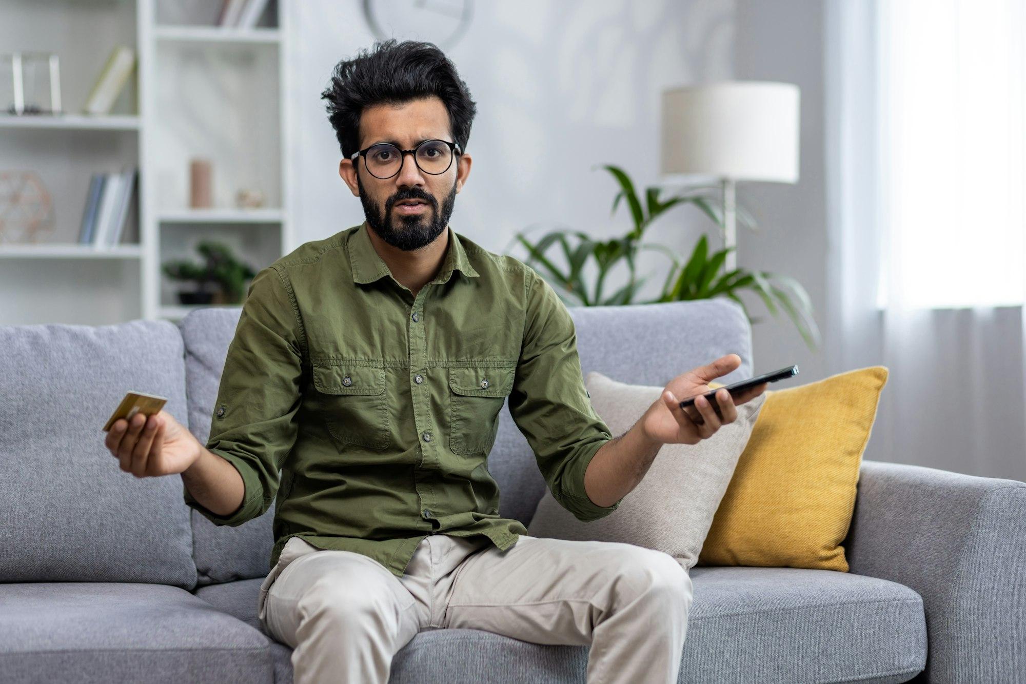 Dissatisfied and disappointed indian man cheated online by scammers robbers, looking at camera, man